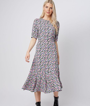 Woman in pink floral frill hem tiered midi dress and black ankle boots