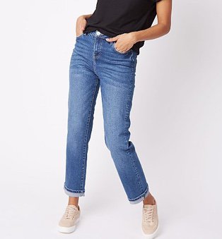 Woman in black top, mid wash denim high rise straight jeans and pink trainers