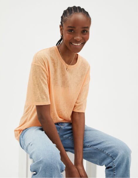 A woman sitting in an orange t-shirt and jeans