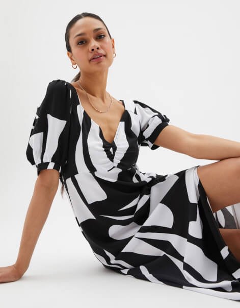 A woman sitting on the floor in a monochrome dress