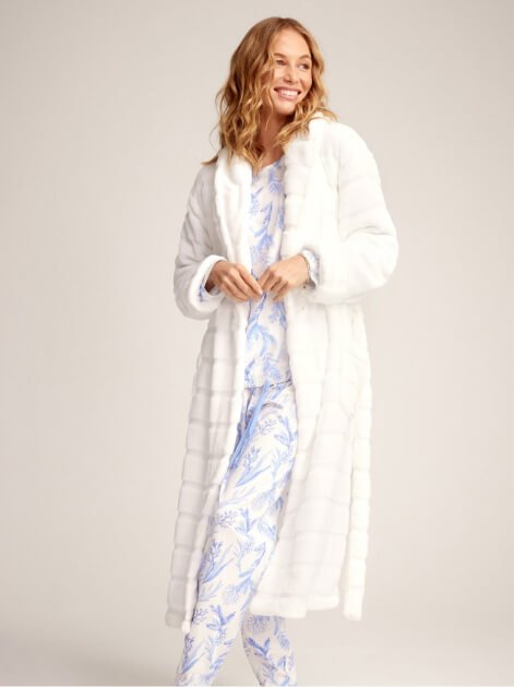A woman posing in blue patterned pyjamas and a white dressing gown