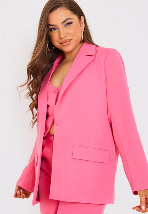 A woman posing in a pink co-ord outfit with tailored blazer.