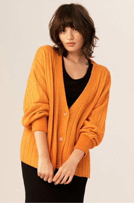 A woman wearing an orange cardigan.