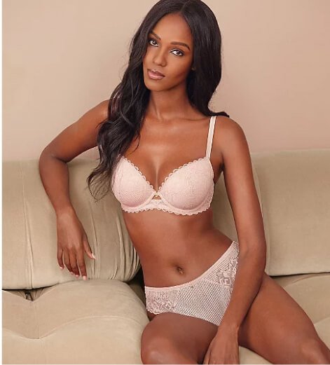 A woman posing in a pink lace bra and knickers set