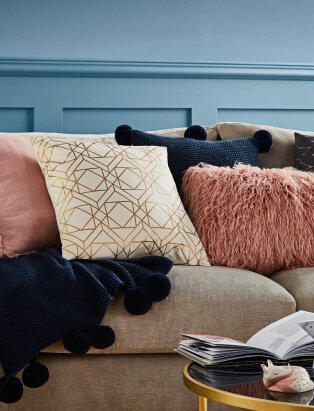 Couch with coloured cushions and black pom pom throw.