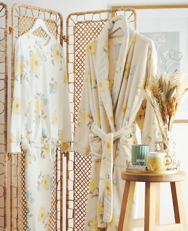 A dressing gown and matching pyjama set hanging from a rattan room divider