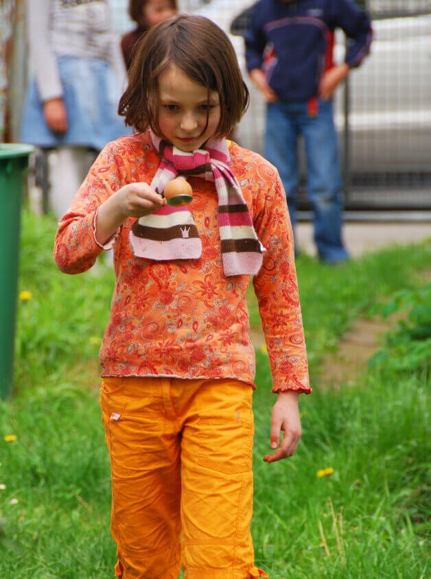 A child in an orange outfit taking part in an egg and spoon race