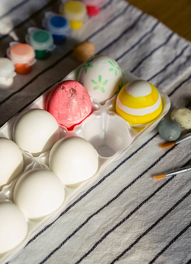 An egg tray with a selection of plain and decorated eggs