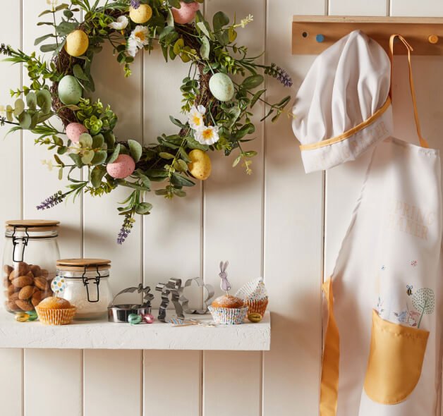 An Easter wreath with pastel egg decorations hanging on a wooden wall