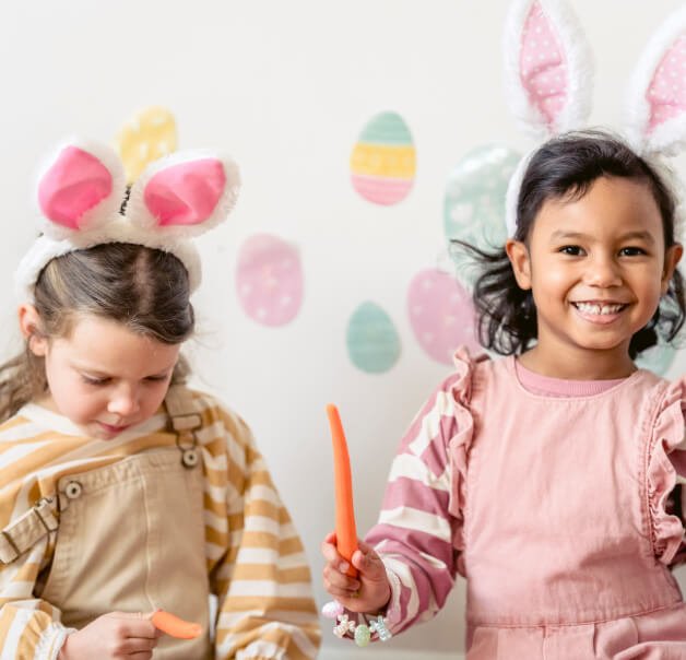 Two children in pastel Easter outfits with bunny ears