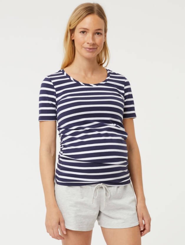 A woman wearing a striped t-shirt and white shorts.