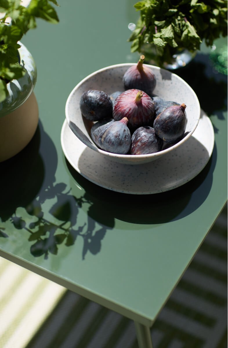A bowl of figs on a garden table.