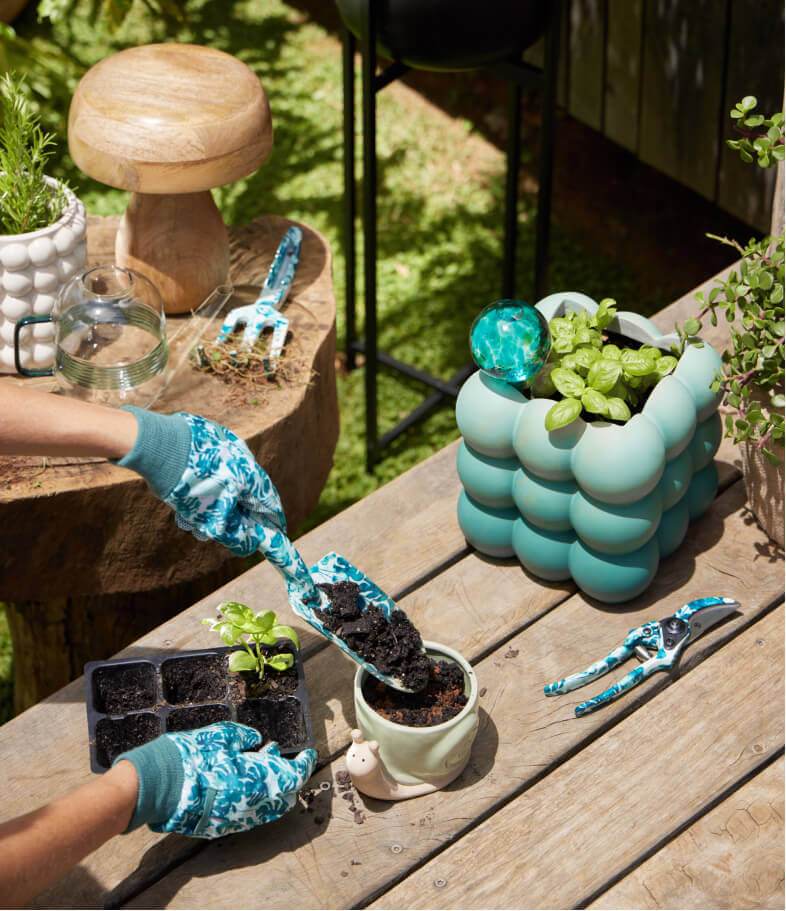 A person gardening using a blue patterned garden tool and glove set.