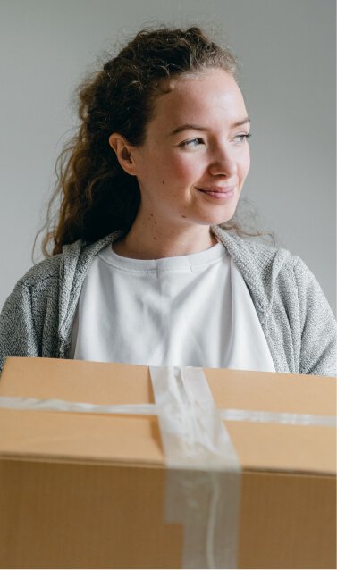 A smiling woman holding a cardboard box.