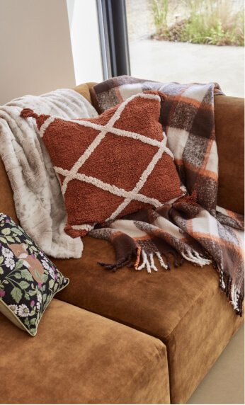 A close shot of a tan sofa with coordinated cushion and throws.