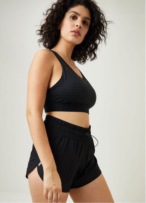 A woman wearing a black sports bra and shorts outfit.