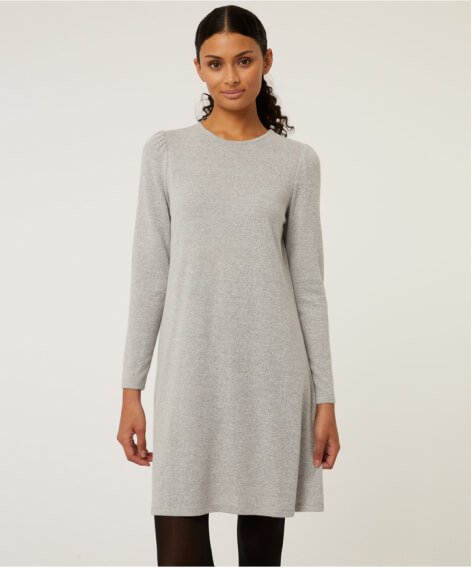 A woman wearing a grey knitted jumper dress over black trousers.