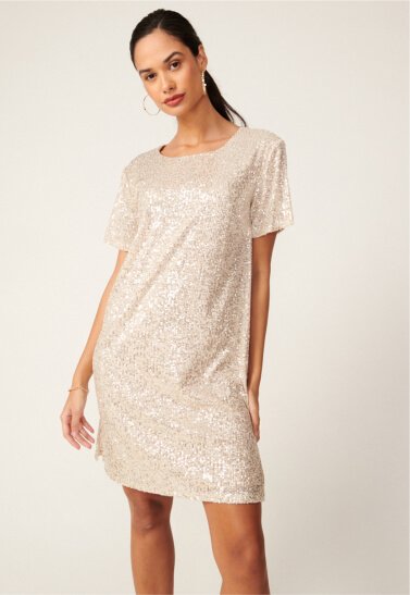 A woman posing in a silver sequin mini dress.