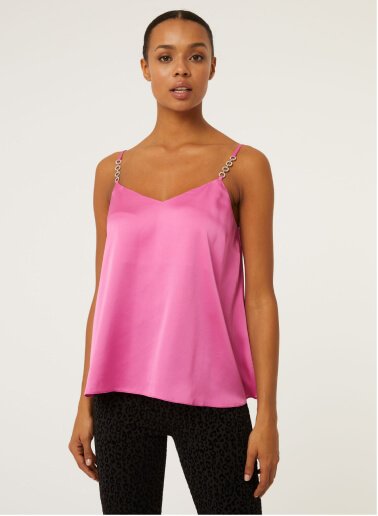 A woman wearing a pink bling strap cami top with black trousers.