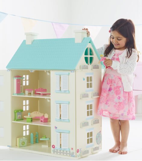 A girl playing with a wooden dolls house
