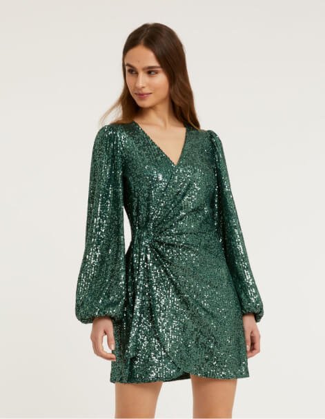 A woman posing in a green sequin wrap dress