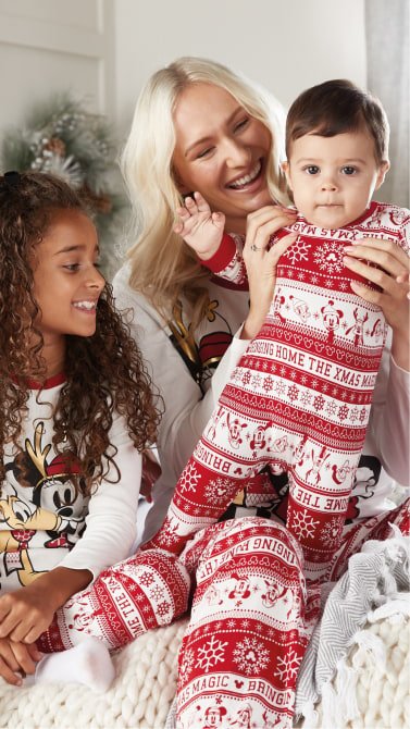 A family of three wearing matching red and white pyjamas