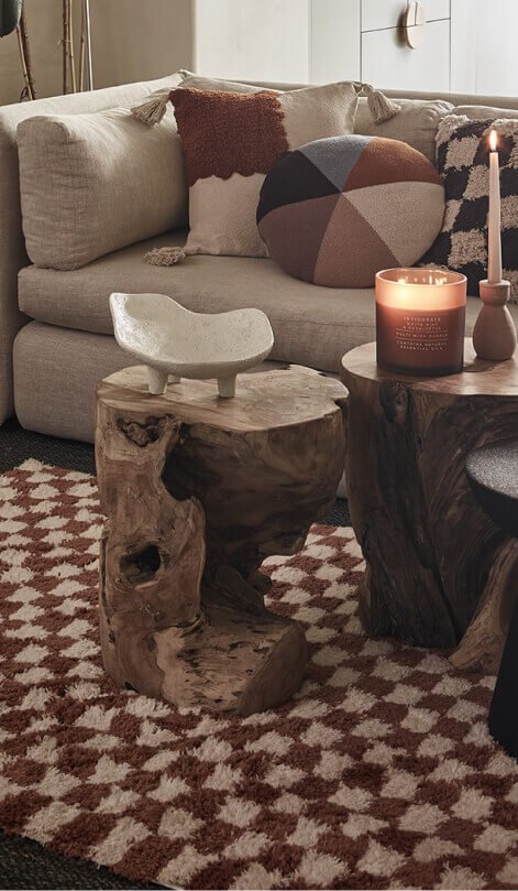 Cream sofa with autumnal cushions. A fluffy rug under a wooden coffee table.