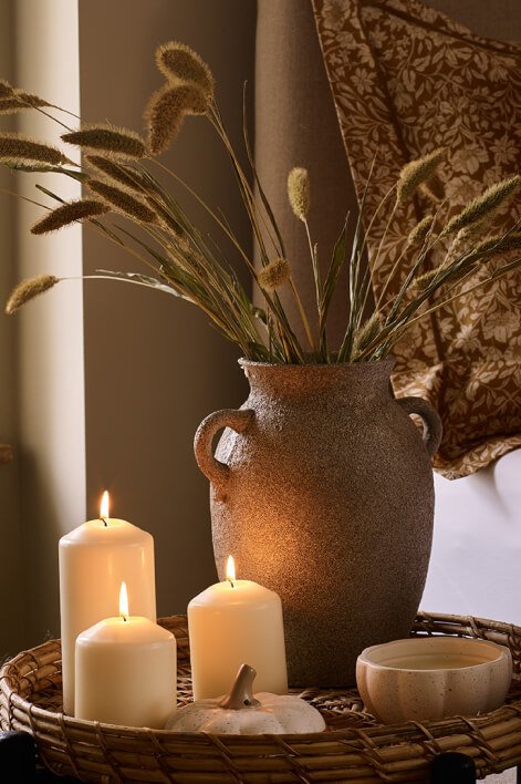 A flower vase beside lit candles.