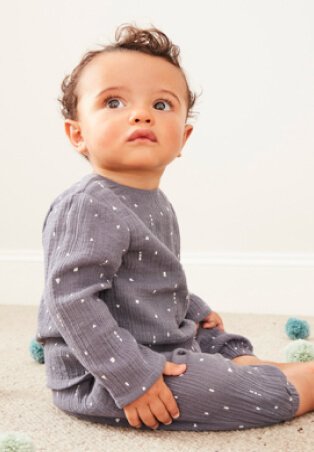 Baby wearing grey and white patterened top and pant set.