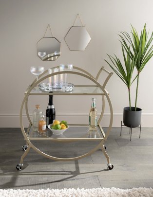 Drinks trolley with glasses, prosecco and fruit on it.
