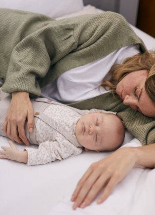 A woman and baby lying together.