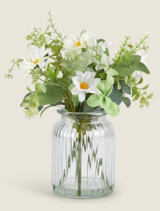 A vase with green foliage and white flowers in.