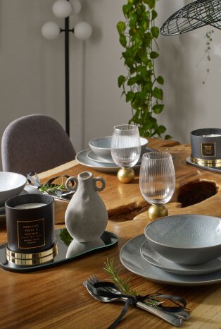 A dinner table with grey dinnerware and glasses with gold-tone accents.