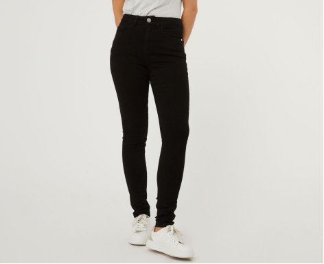 A woman wearing black skinny jeans with white trainers
