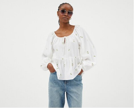 A woman wearing a white blouse with jeans and sunglasses