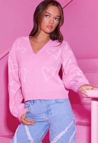Woman wearing pink jumper with white hearts and jeans.