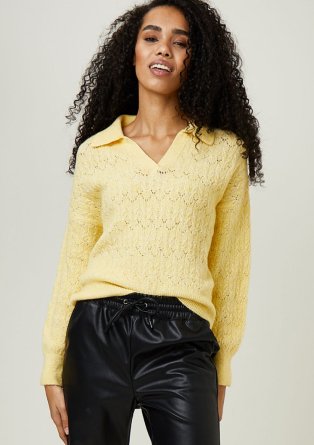 Woman wearing yellow jumper and black PU trousers.