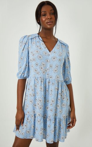 Woman wearing blue tiered dress with floral print.
