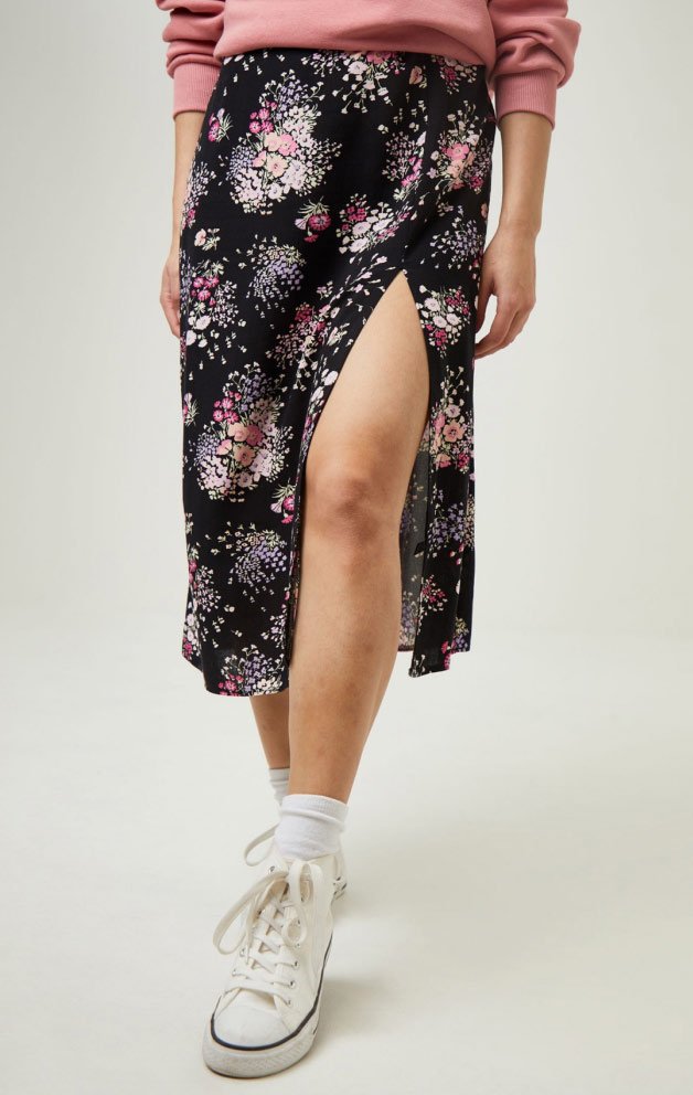 Woman wearing floral print skirt and trainers.