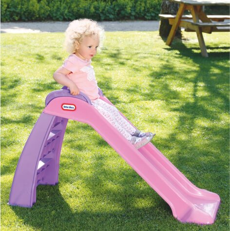 A baby on a slide in the garden. 