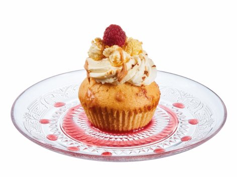 A vanilla cupcake with buttercream, a raspberry and caramel drizzle on a glass plate.