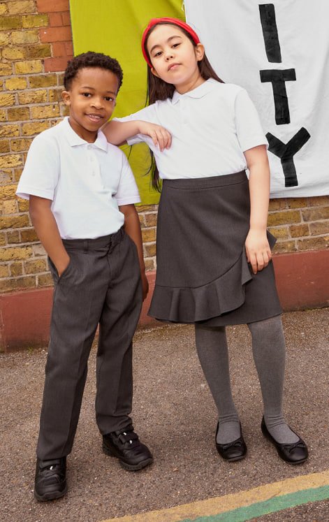 Two school kids standing together in grey and white school uniforms.