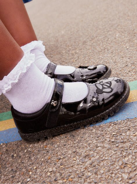A close shot of a girl wearing white ankle socks and black patent school shoes.