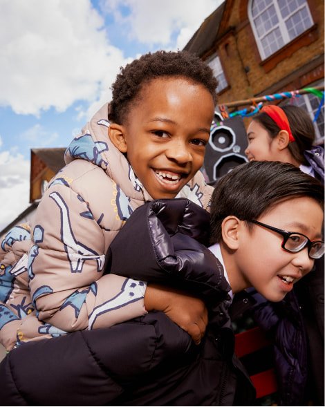 Two kids giving piggy backs, each wearing a different style puffer coat.