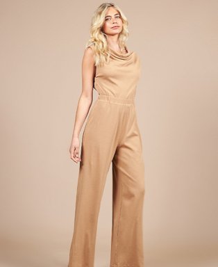 Woman poses wearing Girls On Film camel jersey jumpsuit.