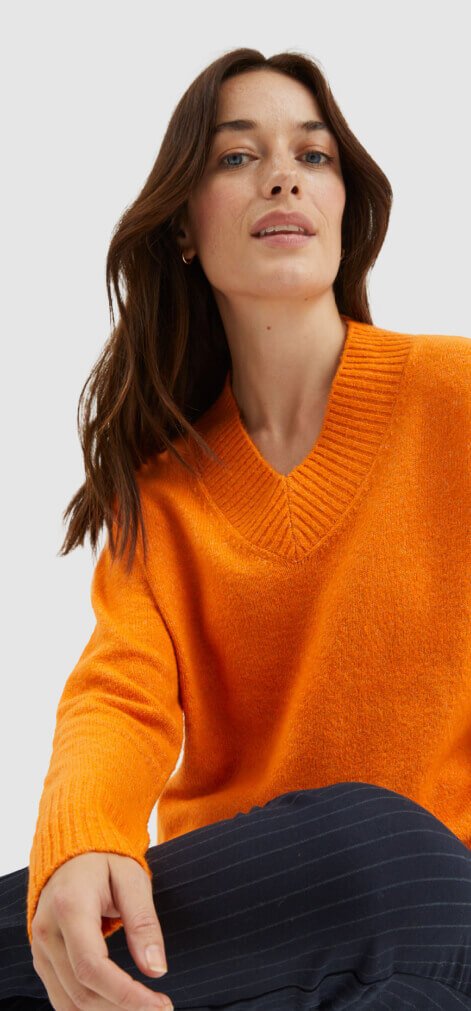 Woman wearing an orange knit jumper.
