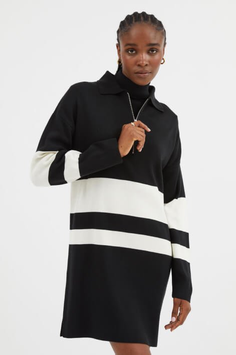 Woman wearing a long knit black dress with white stripes.