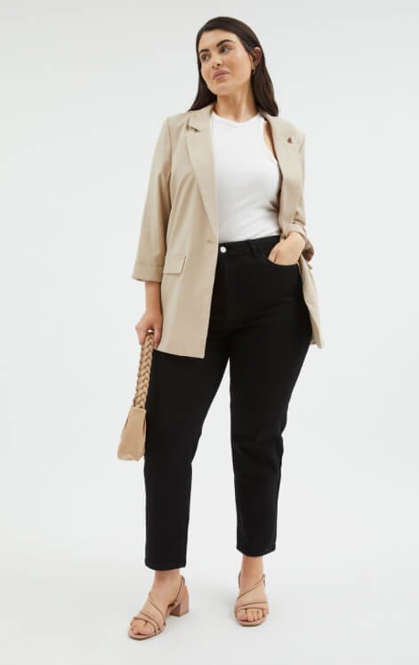 Woman wearing beige blazer with a white top and black trousers.