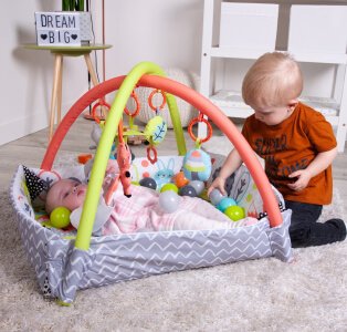 Baby play mat with toys with a baby and toddler playing.