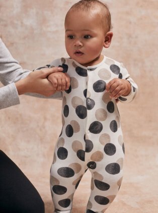 Baby wearing spotted onesie.